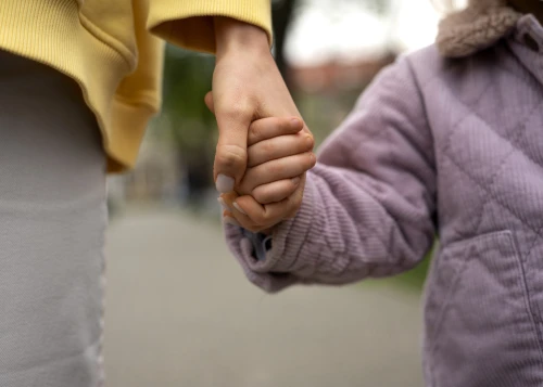 A closeup of an adult and child holding hands.