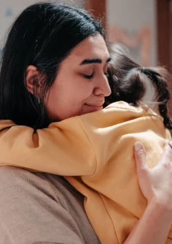 Mother hugging child.
